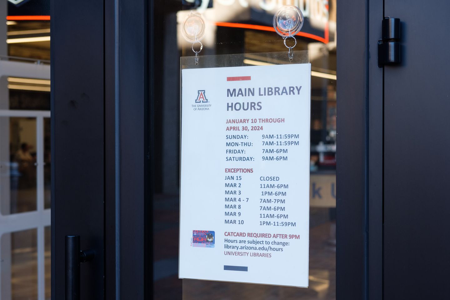 Library door sign that shows hours of operation